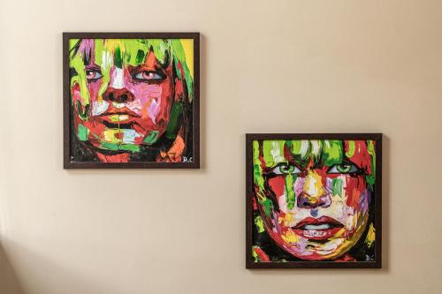 two paintings of men hanging on a wall at White Monkey Villa - Private Pool & Jacuzzi in Pantai Cenang