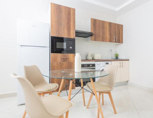 a kitchen with a glass table and white chairs at Magnifique 2 pièces rénové aux Sources in Vieux Kouba