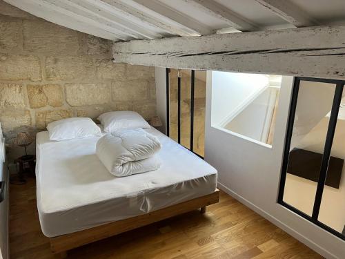 un lit avec des draps blancs et des oreillers dans une chambre dans l'établissement Casa Berlioz, à Montpellier