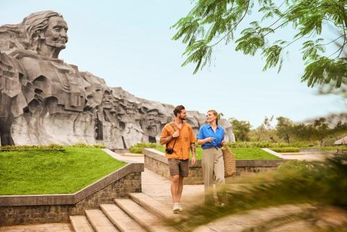 a man and woman walking in front of a statue at ROBINSON Nam Hoi An in Tam Ky
