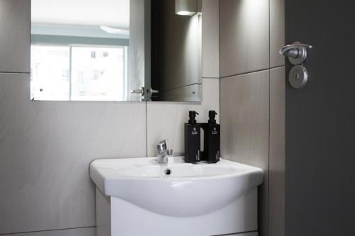 a bathroom with a white sink and a mirror at Ocean Breeze Hotel in Strand