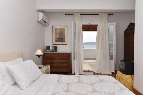 Un dormitorio con una cama blanca y una ventana. en Cycladic home in Kampos by GHH, en Kampos