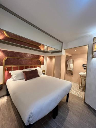 a bedroom with a large white bed and a bathroom at Hotel Du Cadran in Paris