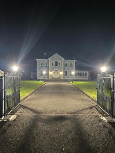 a large white house at night with a gate at Mongalvin in Whitehill