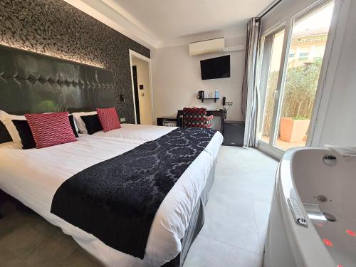 a bedroom with a large bed and a bath tub at Nyx Hôtel Indépendant Perpignan Centre Gare in Perpignan