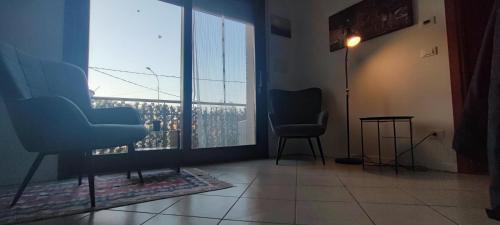 a waiting room with two chairs and a large window at Appartamento Via San Vitale in Tabellini