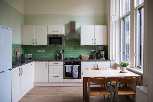 a kitchen with white cabinets and a wooden table at 7 Crown Gardens Glasgow in Glasgow