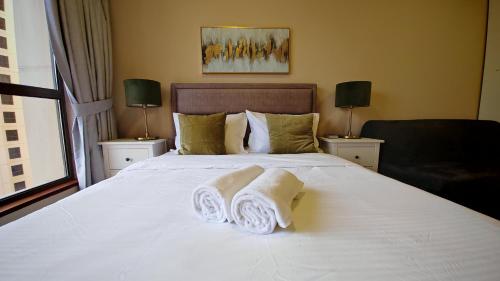 a bedroom with a large white bed with towels on it at Modern, spacious, Luxe 5BR plus Maid condo in JBR, near JBR Beach, Marina view, By La Buena Vida Holiday Homes in Dubai
