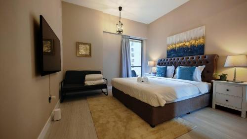 a bedroom with a large bed and a chair at Modern, spacious, Luxe 5BR plus Maid condo in JBR, near JBR Beach, Marina view, By La Buena Vida Holiday Homes in Dubai