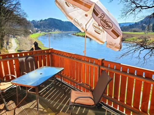 a table and chairs and an umbrella on a deck at Café am Hirschgrund in Kurort Rathen