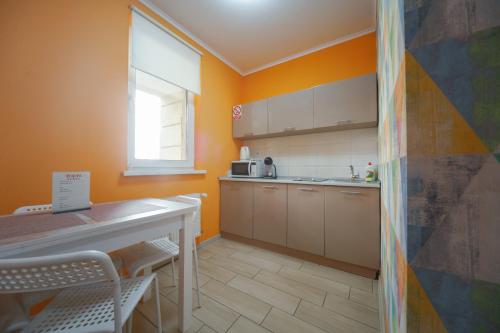 a kitchen with orange walls and a table and a window at BonApart in Lviv