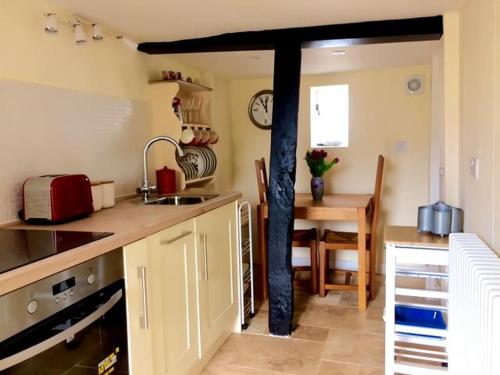 a kitchen with a sink and a table with a clock at Cosy and unique Thatched Cottage on Dartmoor in Bridford