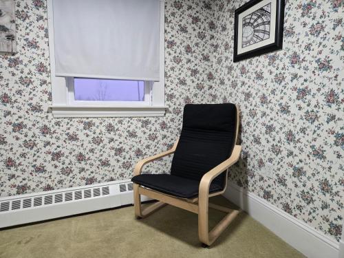 a chair in a room with floral wallpaper at Milford Rd room 2 in Saint John
