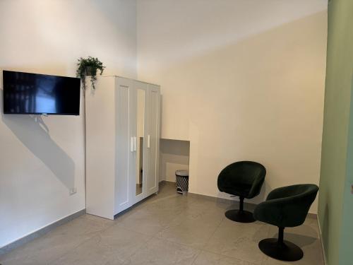 a room with two chairs and a tv on the wall at Casa Giulia in Portici
