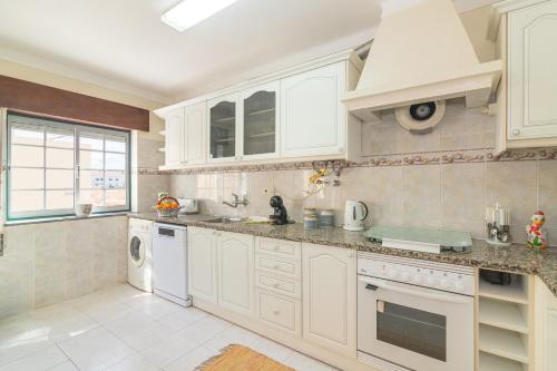 a kitchen with white cabinets and a sink at Casa do Sol - Estombar, Algarve in Estômbar
