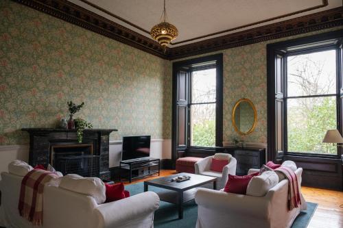 a living room with white chairs and a television at 7 Crown Gardens Glasgow in Glasgow