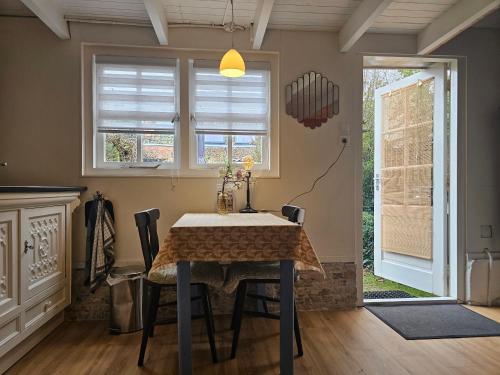 a dining room with a table and chairs and windows at Omas kleine huisje in Veere