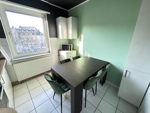 a kitchen with a table and chairs and a window at Ferienapartment Saarbrücken Zentrumsnah mit Luxus-Heimkino, Grill, Balkon & Miele Küche in Saarbrücken
