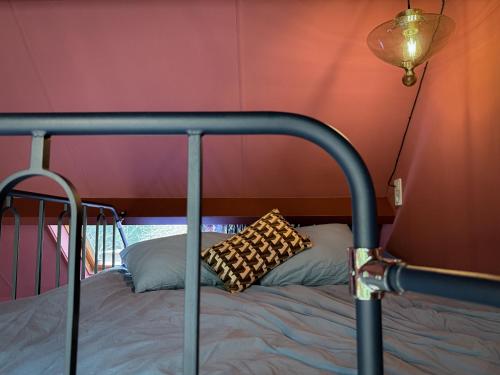 a bed with a metal frame and a pillow on it at Stay Classy - Tiny House in Otterlo