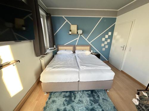 a bedroom with a bed and a blue wall at Ferienapartment Saarbrücken Zentrumsnah mit Luxus-Heimkino, Grill, Balkon & Miele Küche in Saarbrücken