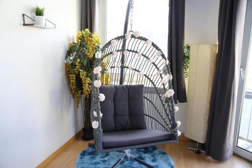 a swing chair in a living room with flowers at Ferienapartment Saarbrücken Zentrumsnah mit Luxus-Heimkino, Grill, Balkon & Miele Küche in Saarbrücken