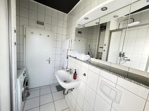 a white bathroom with a sink and a mirror at Ferienapartment Saarbrücken Zentrumsnah mit Luxus-Heimkino, Grill, Balkon & Miele Küche in Saarbrücken