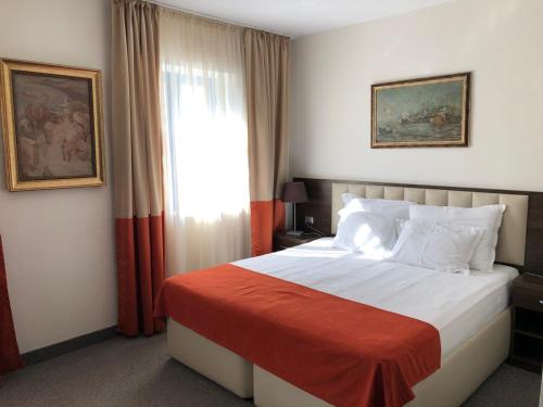 a bedroom with a bed with a red blanket and a window at Семеен хотел Анна-Кристина in Vidin