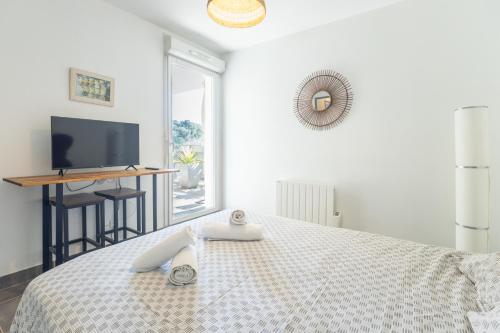 - une chambre avec un lit, une télévision et une table dans l'établissement Le Petit Cocon, à Marseille