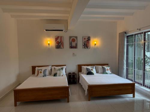a bedroom with two beds and a large window at Dwellio -Ratmalana - Greater Colombo in Ratmalana
