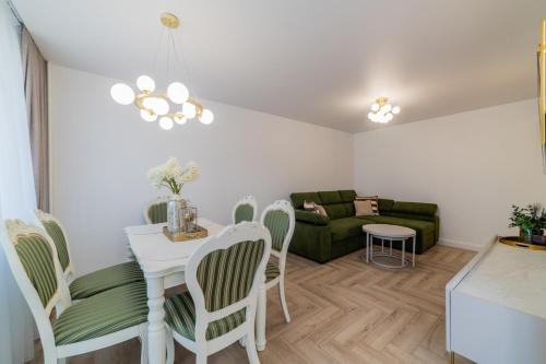 een woonkamer met een tafel, stoelen en een bank bij Frida Luxury Apartments in Šiauliai