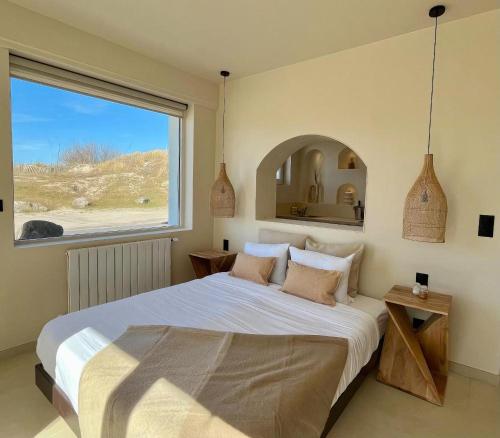 une chambre avec un grand lit avec une grande fenêtre dans l'établissement La Suite Balinaise, vue mer et dunes - MALO'Cation, à Dunkerque