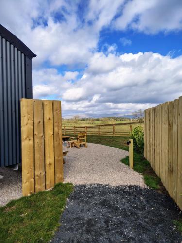 a wooden fence with a picnic table and a bench at Brackenslack Shepherds Huts in Maulds Meaburn