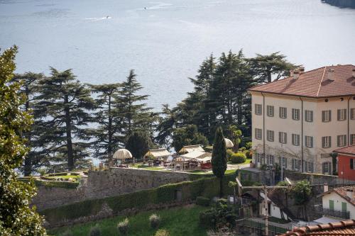 a large white building with trees and the water at Suite panoramica in Guest House in Moltrasio