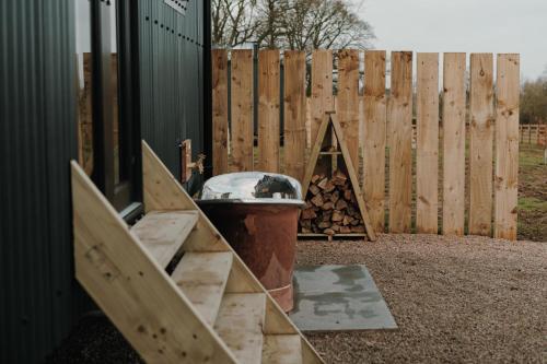 a wooden fence with a grill and a pile of wood at Brackenslack Shepherds Huts in Maulds Meaburn