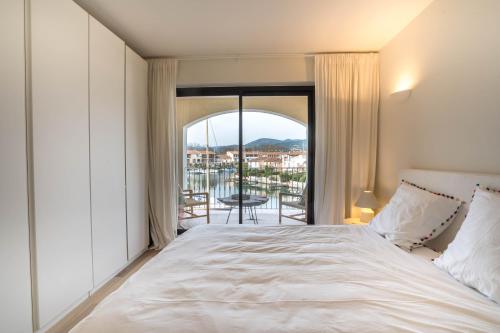 une chambre avec un grand lit et un balcon dans l'établissement Appartement Port Grimaud, à Grimaud