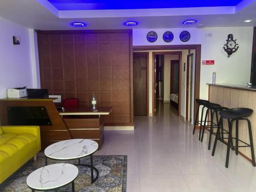 a lobby with a yellow couch and tables and chairs at Naaboli Inn in Hulhumale