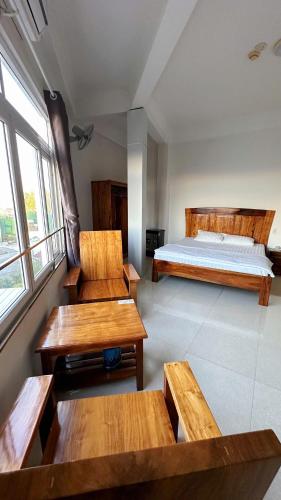 a bedroom with wooden benches and a bed and windows at Trường Ngọc Hotel in Buon Ma Thuot