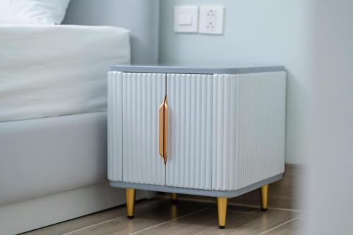 a bedside table with a white cabinet next to a bed at Osen Hotel - Grand World Phu Quoc in Phu Quoc