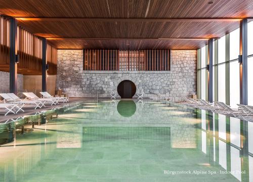 a large swimming pool with chairs in a building at Bürgenstock Residence Suites in Bürgenstock