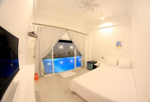 a white bedroom with a large bed and a window at Coron Bluewave Hotel in Coron