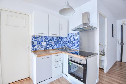 - une cuisine avec du carrelage bleu et blanc sur le mur dans l'établissement Appart 3 ch avec balcon à la Joliette, à Marseille