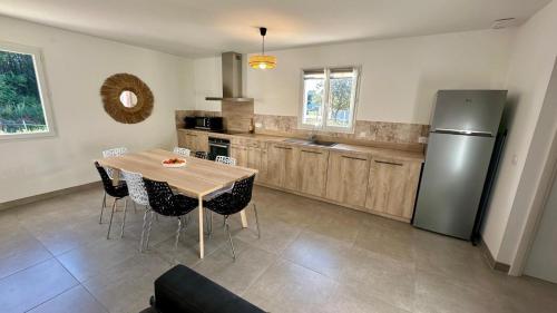 eine Küche mit Tisch und Edelstahlkühlschrank in der Unterkunft "Villa des Bourdaines" in Vielle-Saint-Girons