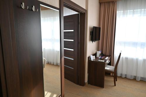 a door to a room with a desk and a mirror at Hotel Centrum Malbork in Malbork