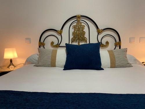 a large bed with blue and white pillows on it at Hostal La Trucha Sanabria in Puebla de Sanabria