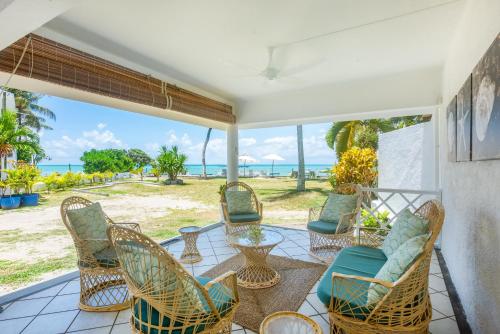 a porch with chairs and tables and a view of the ocean at Quaint 2BDR beach apartment in a fishing village in Grand Gaube