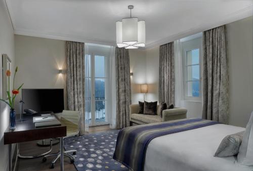 a hotel room with a king sized bed and a desk at Bürgenstock Residence Suites in Bürgenstock