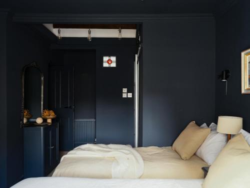 a bedroom with blue walls and a bed with white sheets at Cambridge House in Windermere