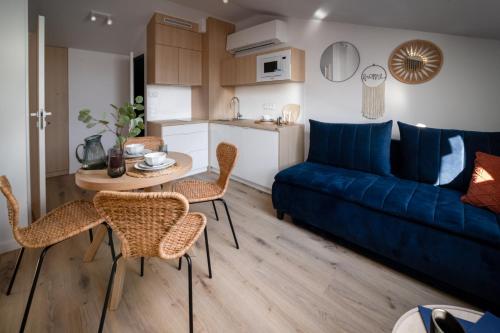a living room with a blue couch and a table and chairs at Apartamenty Wyspa Jastarnia Morski in Jastarnia