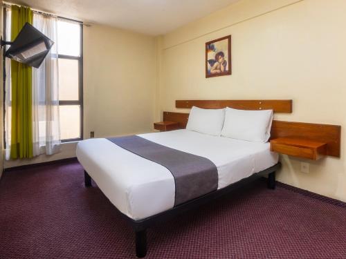 a hotel room with a large bed and a window at Capital O Hotel Suites Marne, Mexico City in Mexico City
