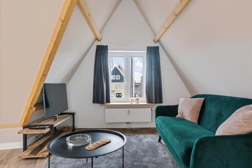 a living room with a green couch and a table at Apartment at the harbor in Monnickendam